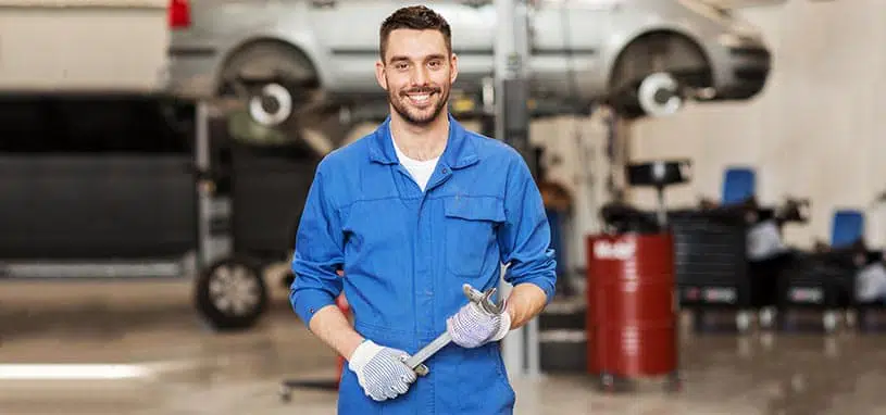 Automotive air conditioning specialist in a workshop holding a service tool.