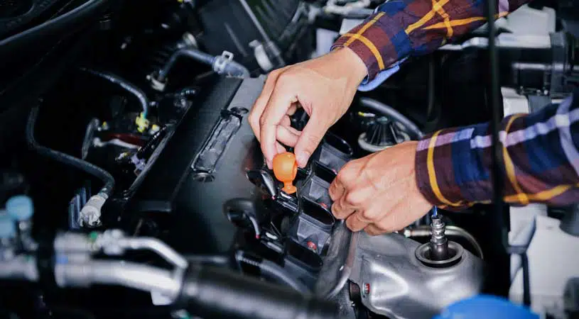 Person checking a car engine under the bonnet.