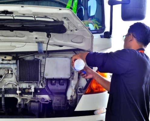truck driver refilling water in truck radiator