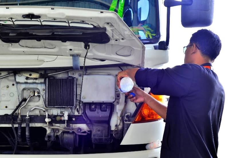 truck driver refilling water in truck radiator