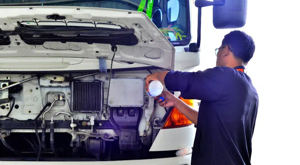 truck driver refilling water in truck radiator