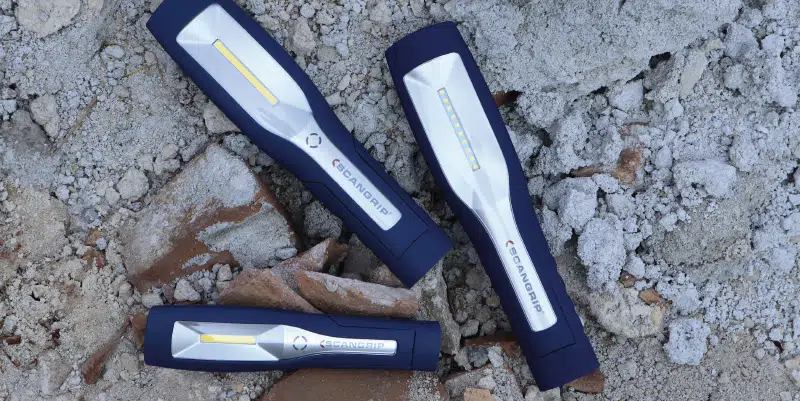 Three LED work lights from SCANGRIP are placed on rubble and broken bricks.