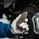 Mechanic holding up a worn brake pad.