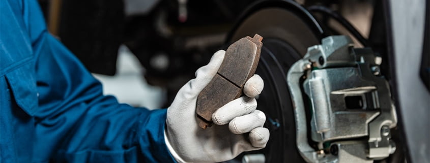 Mechanic holding up a worn brake pad.