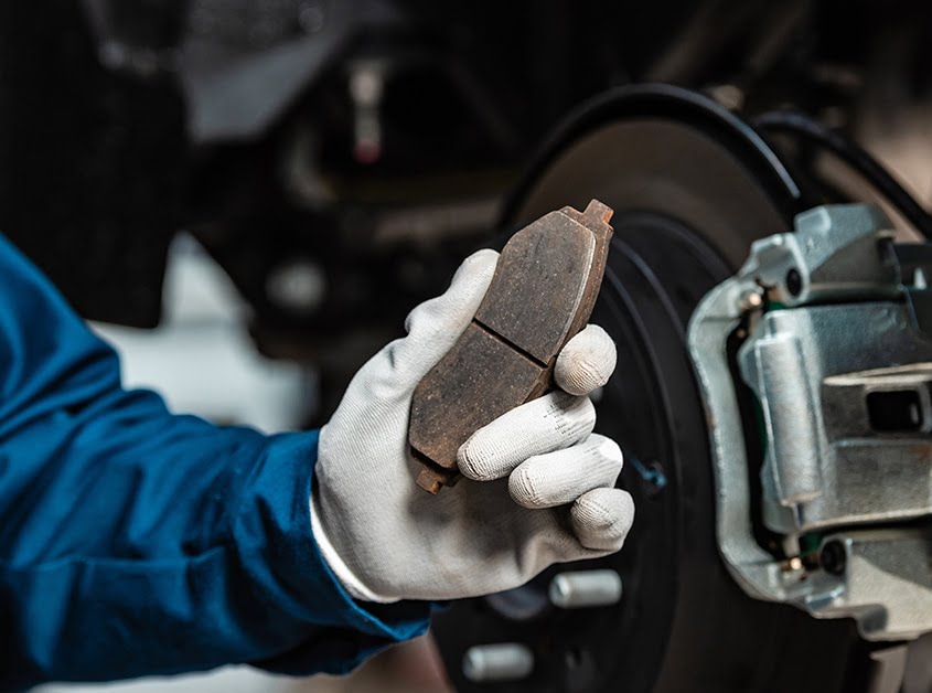 Mechanic holding up a worn brake pad.