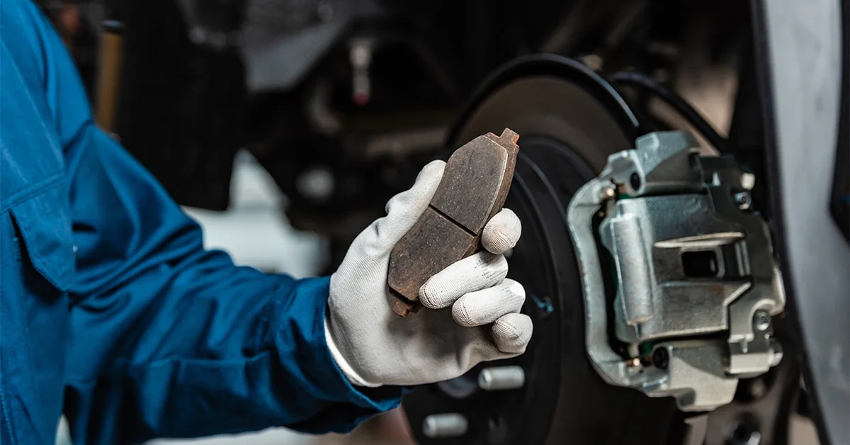 Mechanic holding up a worn brake pad.