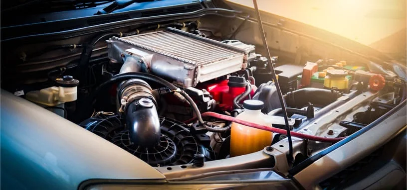 An open car bonnet reveals a detailed view of the engine bay, featuring a top-mounted intercooler and fluid reservoirs.