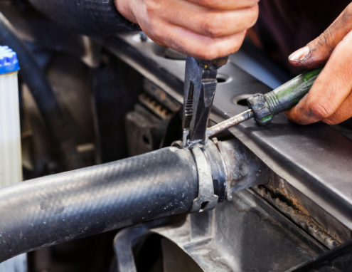 Mechanic removing a radiator hose during a car radiator replacement.