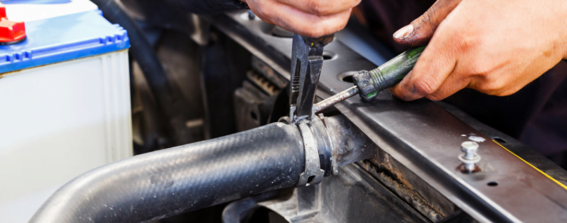 Mechanic removing a radiator hose during a car radiator replacement.