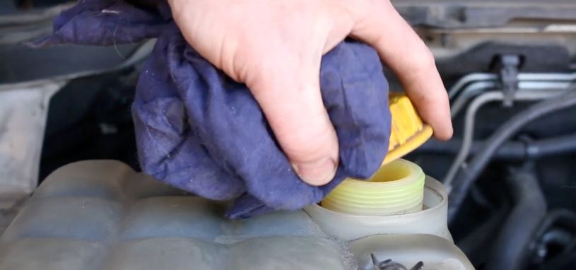 A Natrad specialist removing a cooling system cap using a rag to protect his hand from heated, pressurised coolant.