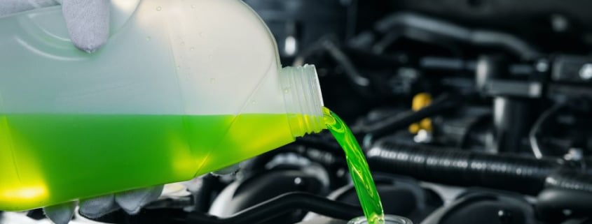 A mechanic pouring coolant directly into a car’s radiator