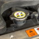 A closeup of a clearly marked radiator cap within a car.