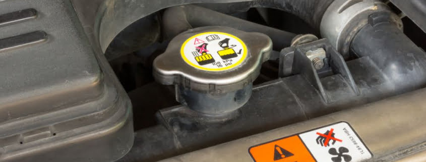 A closeup of a clearly marked radiator cap within a car.