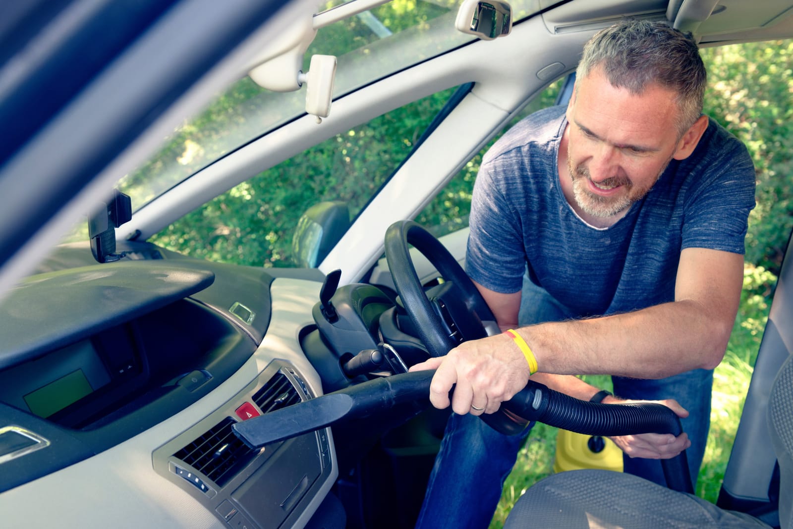 Man hoovering air vent in car