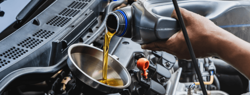 Car mechanic pouring engine oil into vehicle during doing car maintenance in garage