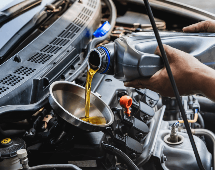 Car mechanic pouring engine oil into vehicle during doing car maintenance in garage