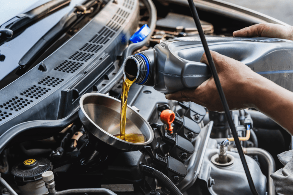 Car mechanic pouring engine oil into vehicle during doing car maintenance in garage