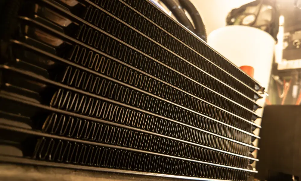 Close-up view of a car radiator showing metal cooling fins and heat exchange structure.