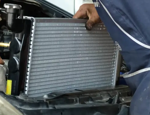 Mechanic installing a car radiator in the engine bay during vehicle maintenance.