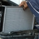 Mechanic installing a car radiator in the engine bay during vehicle maintenance.