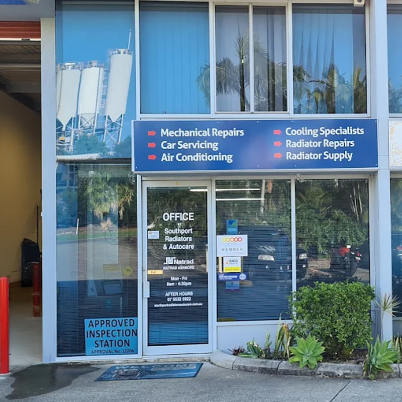 Exterior view of the radiator shop office entrance with service signage and a neighbouring storefront.