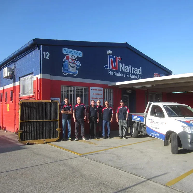 Exterior view of the red and blue Natrad workshop with the team out front.